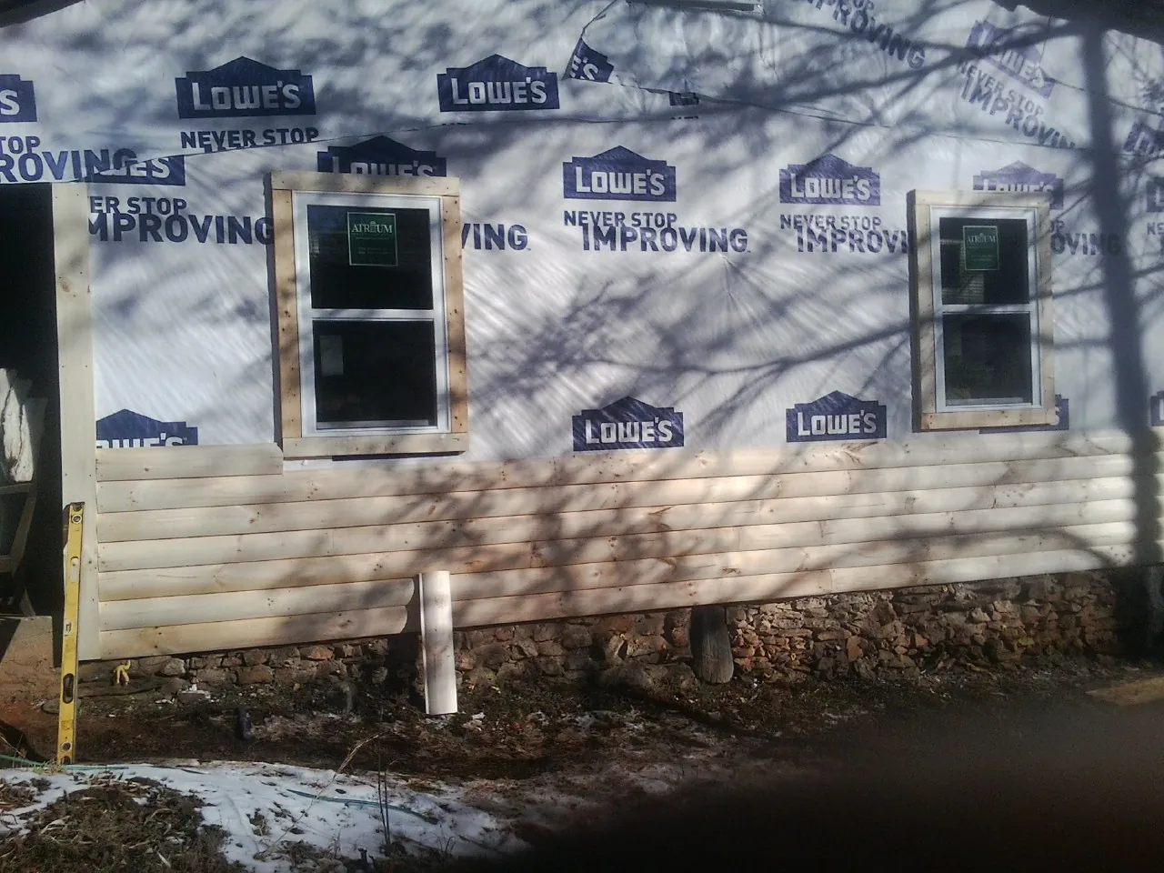 House wrap and new log siding going up on an exterior wall in Forest Park