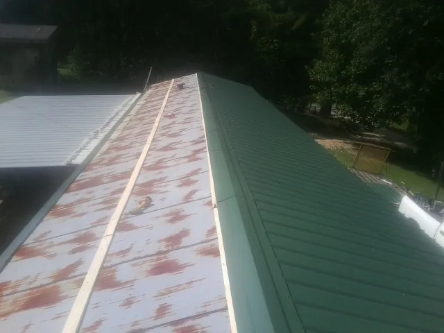 Old rusted panels beside newly installed green metal roofing — Wind Damage Roof Repair by Roofing Brothers in Forest Park