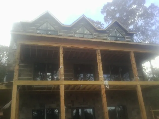 Dormers and porch framing on a large log home under construction — Roof Coating work by our crew in Forest Park