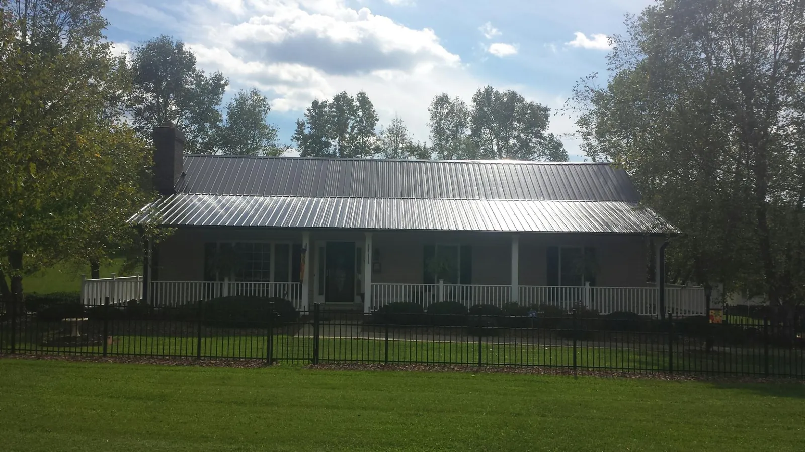 Gray metal roof on a brick ranch with a full width front porch — Gutter Guard Installation work by our crew in Forest Park