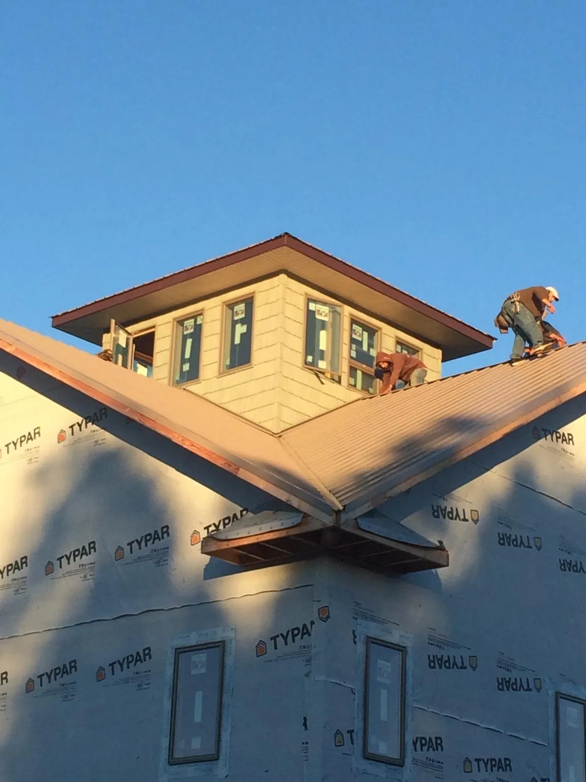 Roofers working around a rooftop cupola on a new metal roof at sunset — Roof Waterproofing in Forest Park by Roofing Brothers